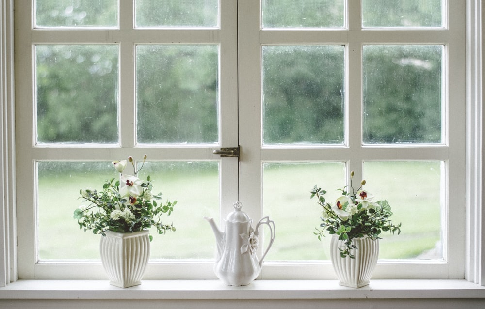 white teapot and flower vases on windowpane